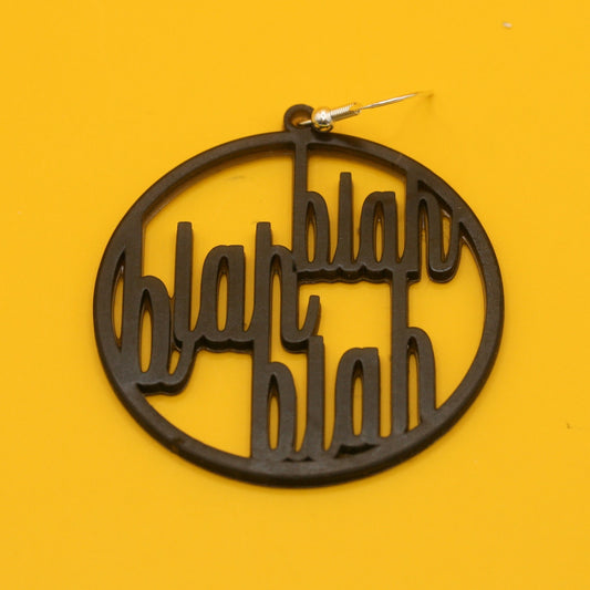 Black circular word art earring that says "Blah, blah, blah" in retro font